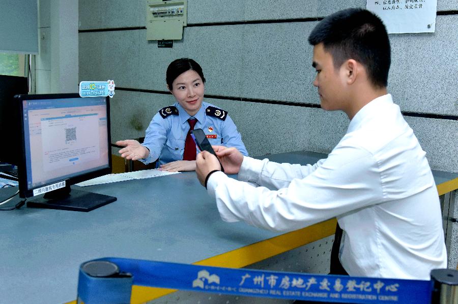 纳税人缴费人正在广州市房地产交易登记中心扫码体验“税费金一码清”服务。
